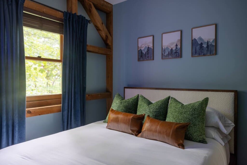 Mountain-themed bedroom with blue walls and watercolor prints at Peak and Pine Retreat