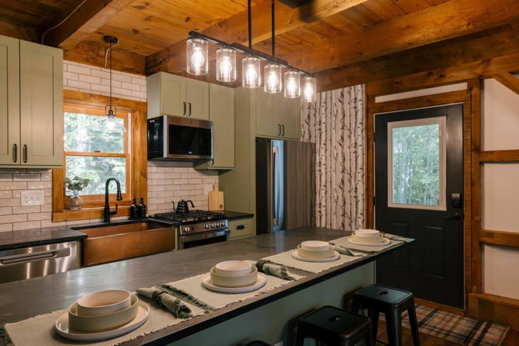 Renovated luxury kitchen with copper farmhouse sink, gas range, and breakfast bar at Peak and Pine Retreat