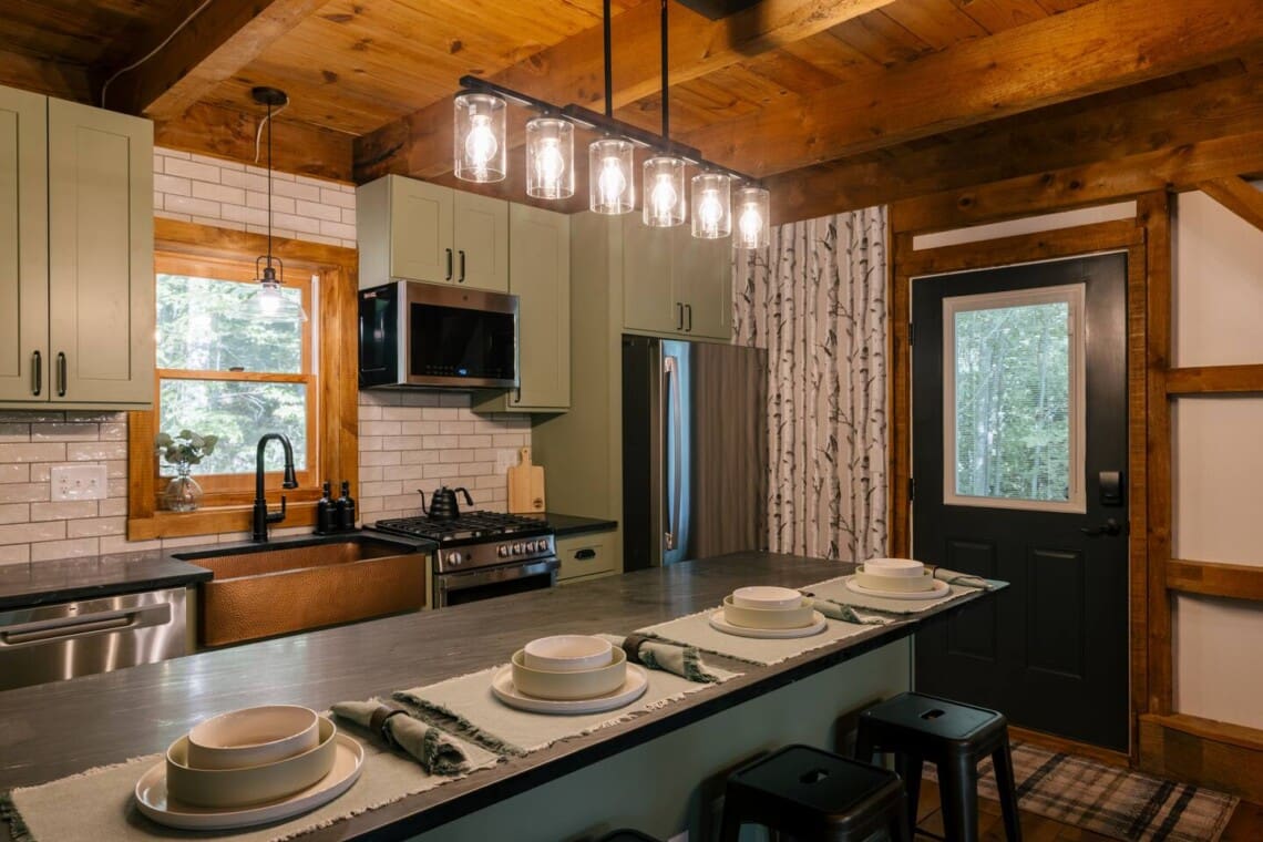 Renovated luxury kitchen with copper farmhouse sink, gas range, and breakfast bar at Peak and Pine Retreat