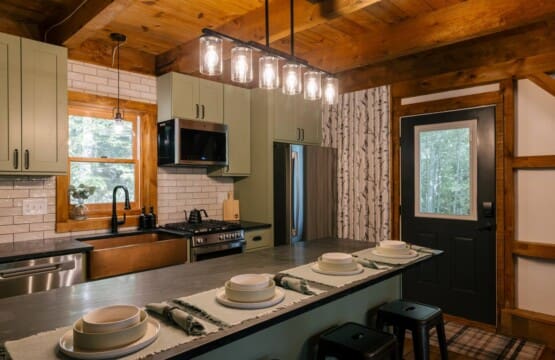 Renovated luxury kitchen with copper farmhouse sink, gas range, and breakfast bar at Peak and Pine Retreat