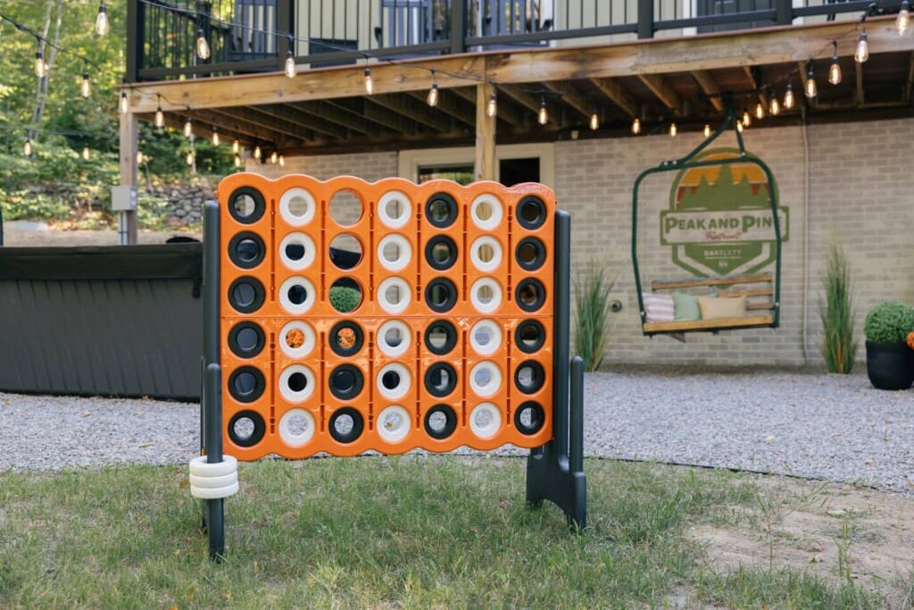 Giant Connect Four lawn game in the backyard at Peak and Pine Retreat with string lights