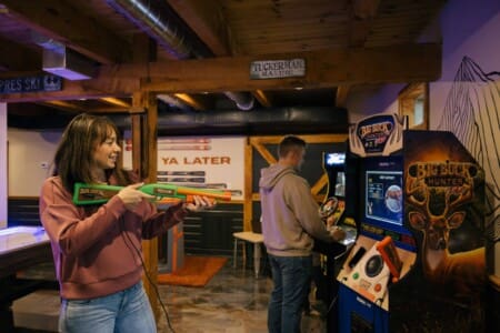 Guests playing Big Buck Hunter arcade games in the game room at Peak and Pine Retreat Bartlett NH