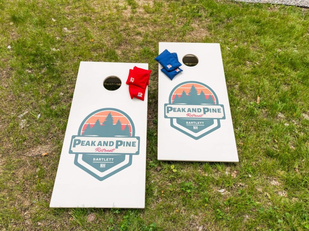 Peak and Pine branded cornhole boards with bean bags set up on the lawn