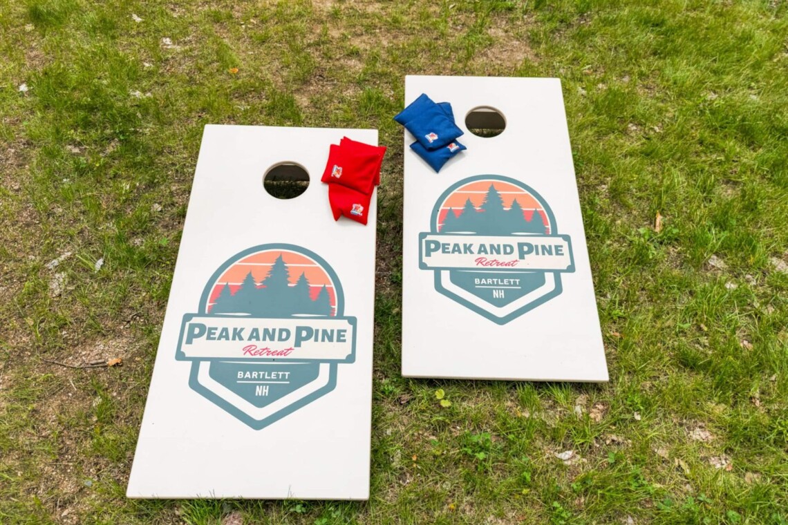 Peak and Pine branded cornhole boards with bean bags set up on the lawn