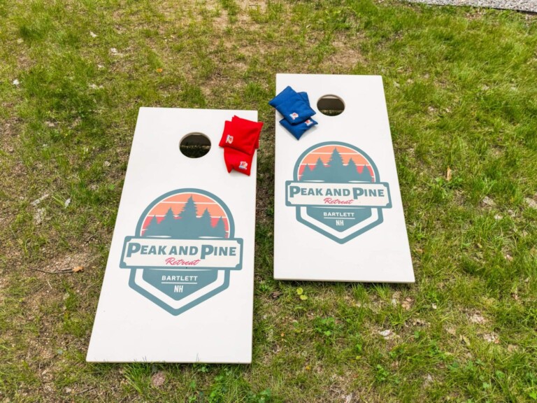 Peak and Pine branded cornhole boards with bean bags set up on the lawn