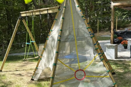 Outdoor play teepee and wooden swing set in the shaded backyard