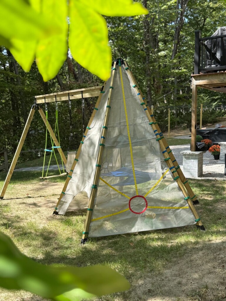 Outdoor play teepee and wooden swing set in the shaded backyard
