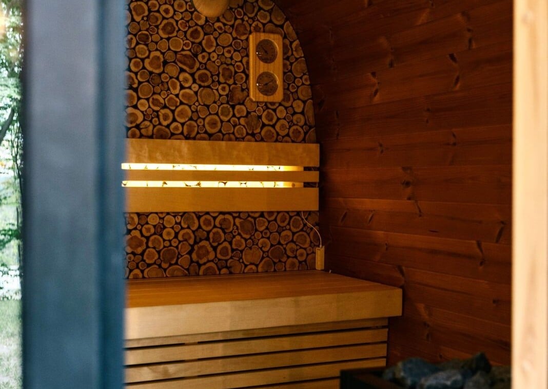 Inside the outdoor sauna with warm-lit wooden benches and sauna heater