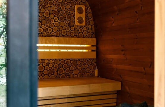 Inside the outdoor sauna with warm-lit wooden benches and sauna heater