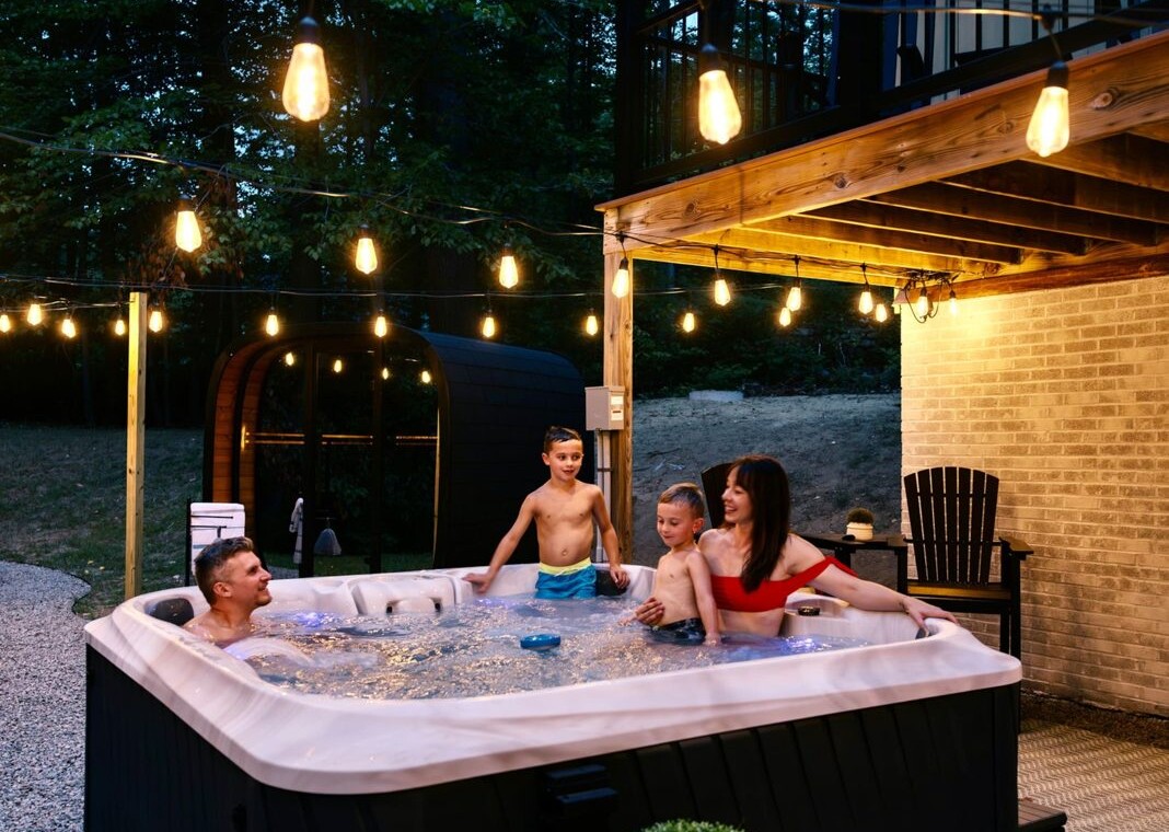 Family enjoying the hot tub at night under backyard string lights