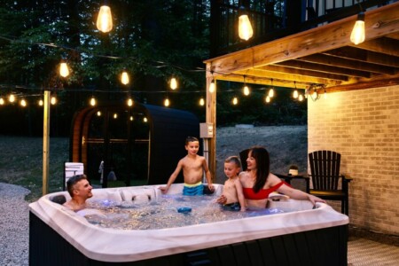Family enjoying the hot tub at night under backyard string lights