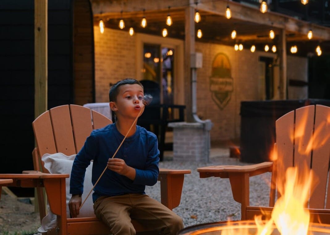 Boy roasting a marshmallow over the fire pit from an Adirondack chair