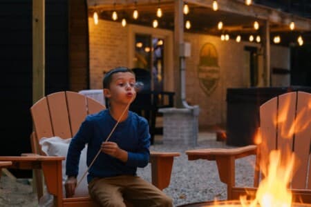Boy roasting a marshmallow over the fire pit from an Adirondack chair