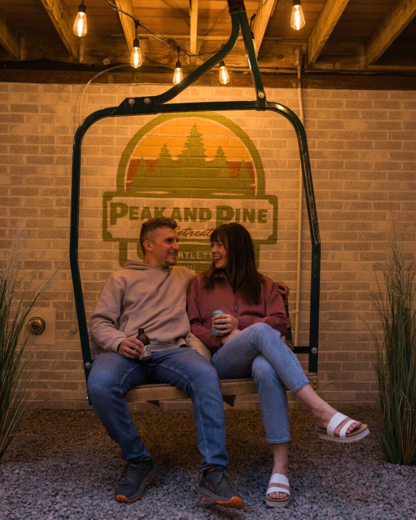 Couple sitting on the ski chairlift swing at night at Peak & Pine Retreat