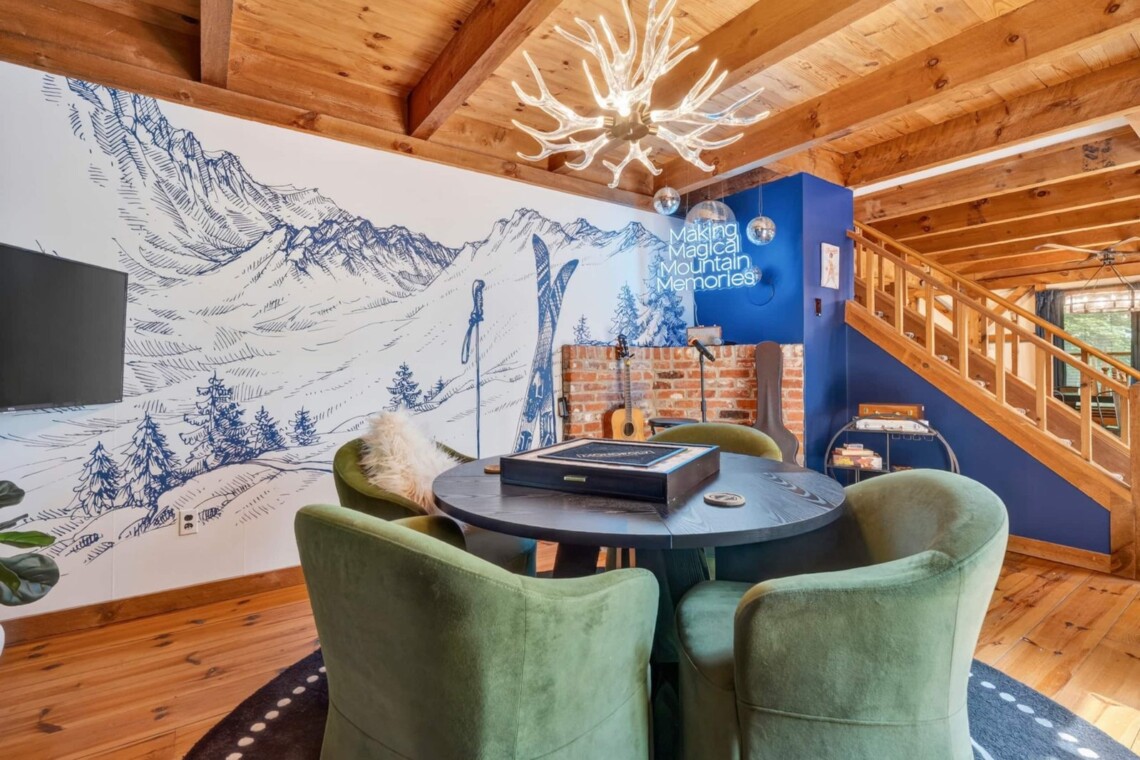 Game nook with round table, antler chandelier and hand-drawn ski mountain mural