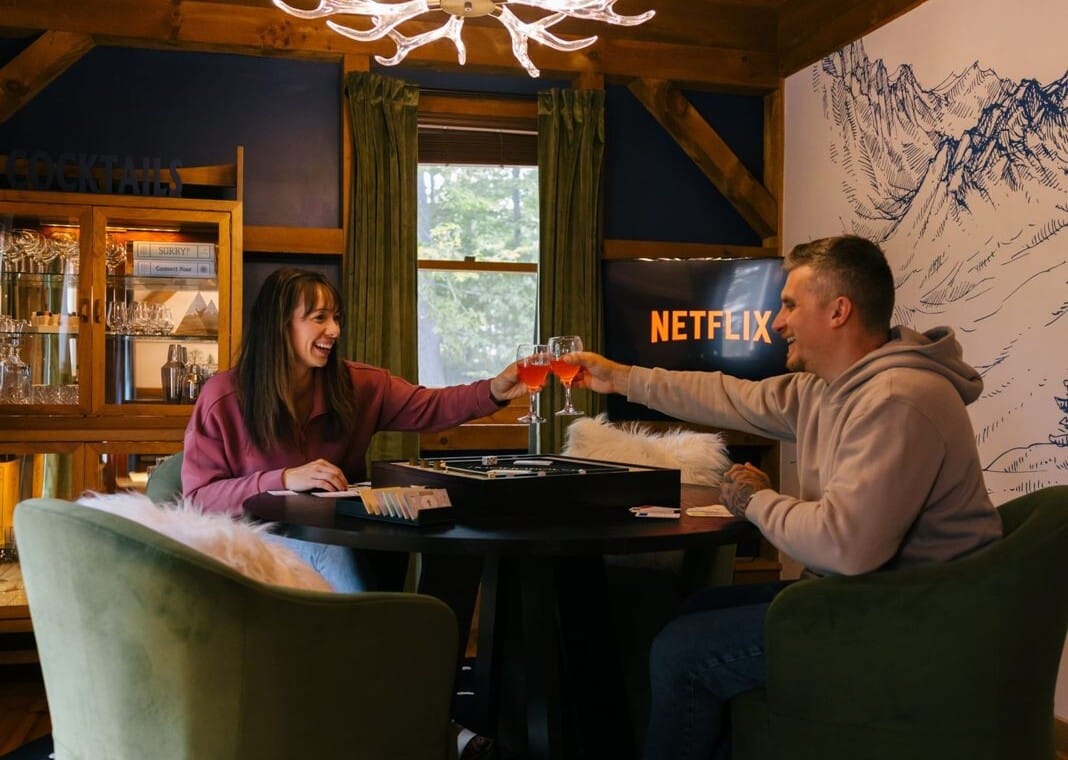 Couple playing a board game under an antler chandelier at Peak & Pine Retreat
