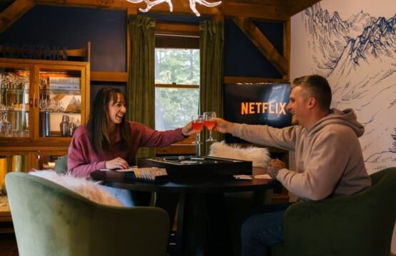 Couple playing a board game under an antler chandelier at Peak & Pine Retreat