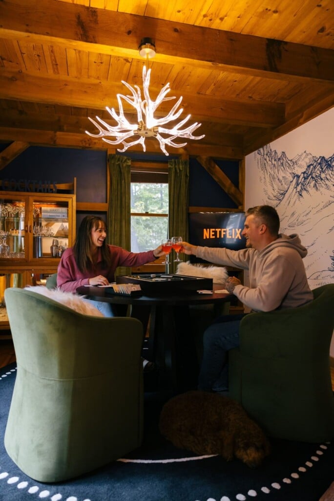 Couple playing a board game under an antler chandelier at Peak & Pine Retreat