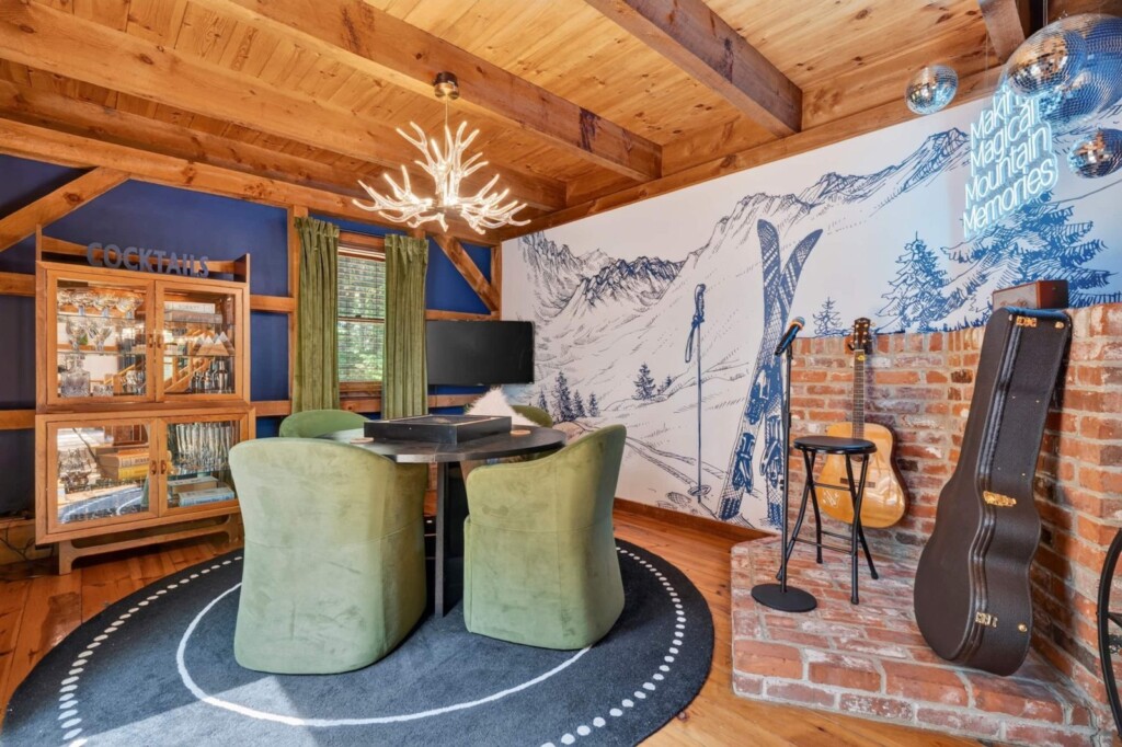 Lounge with acoustic guitars, brick accent wall and green velvet game table chairs