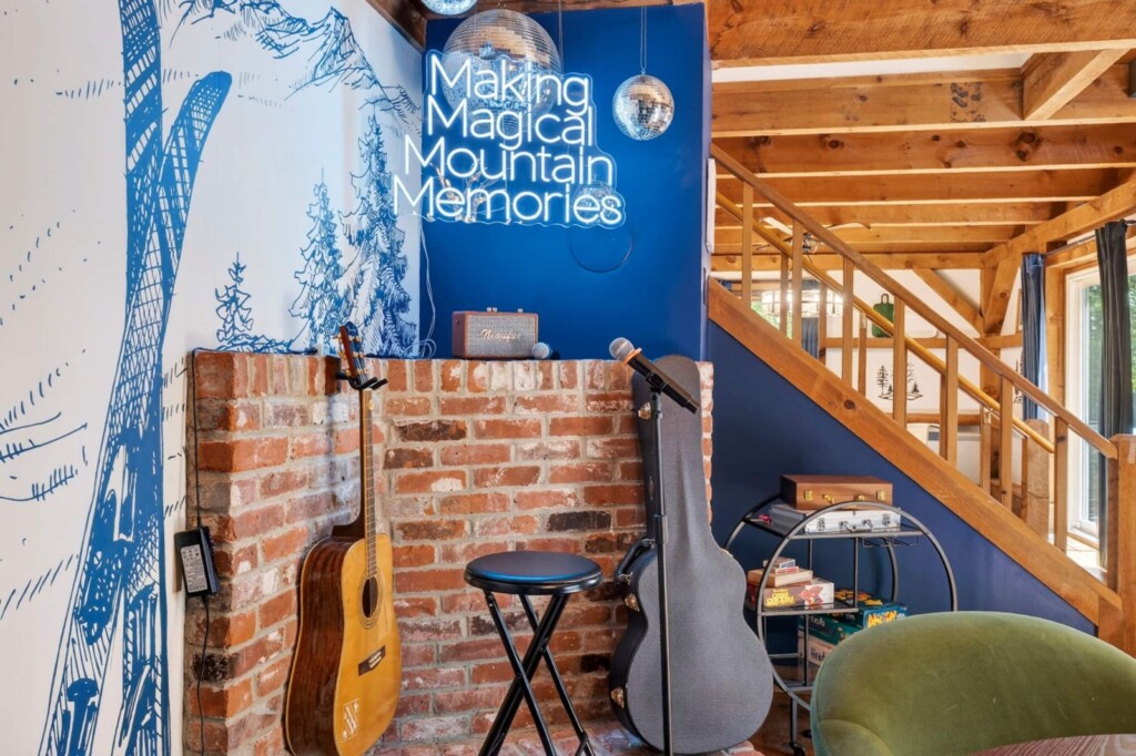 Acoustic guitars and bar stool by a brick wall under the neon sign