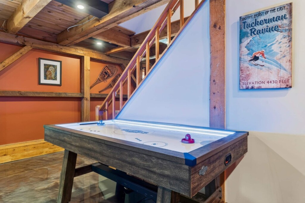 Light-up air hockey table beside the stairs at Peak & Pine Retreat