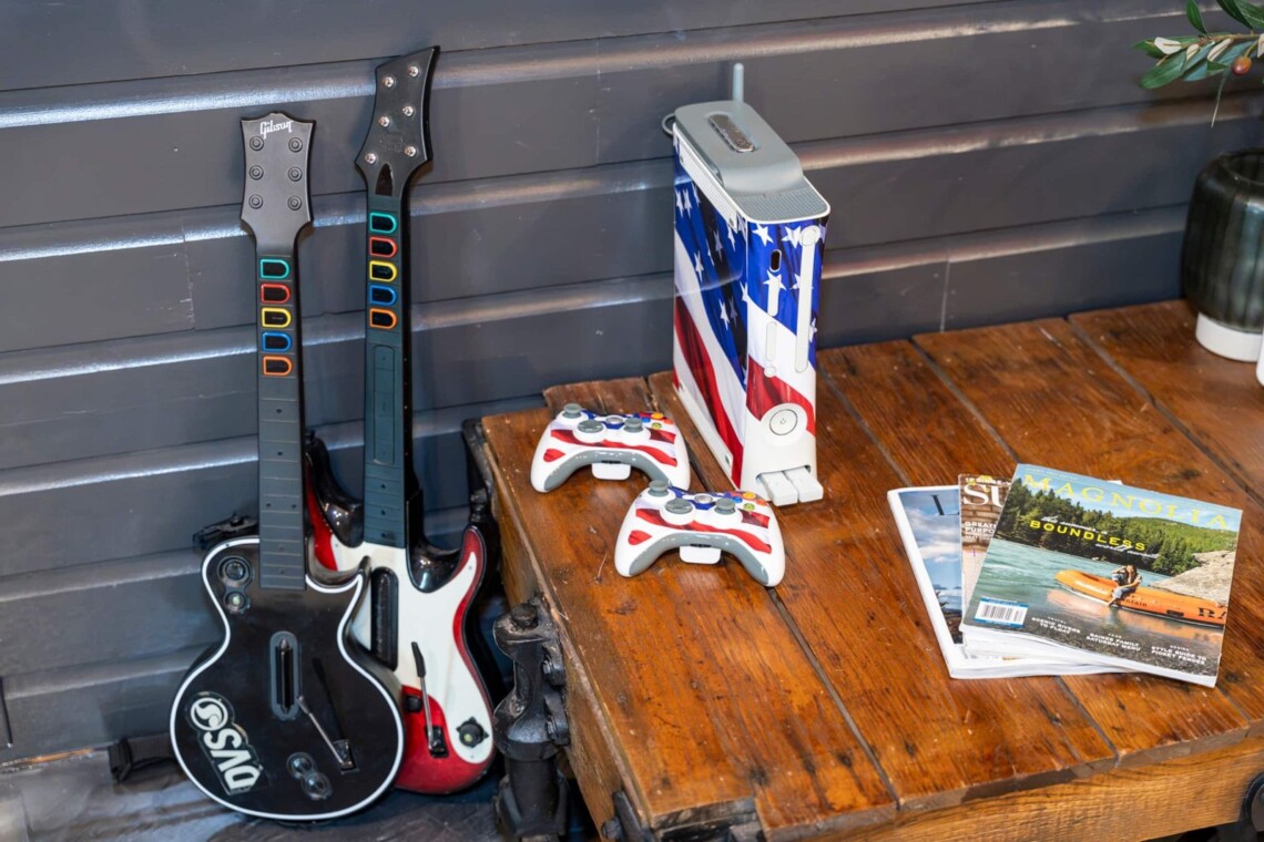 Guitar Hero controllers and Xbox console on a rustic wooden table