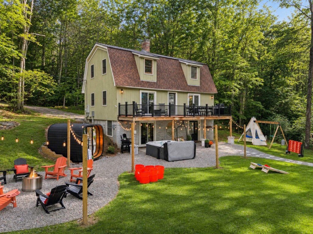Daytime aerial view of the house, deck, sauna, fire pit and swing set