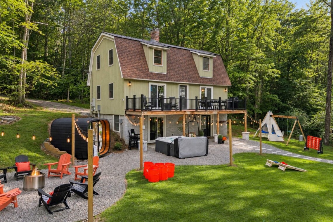 Daytime aerial view of the house, deck, sauna, fire pit and swing set