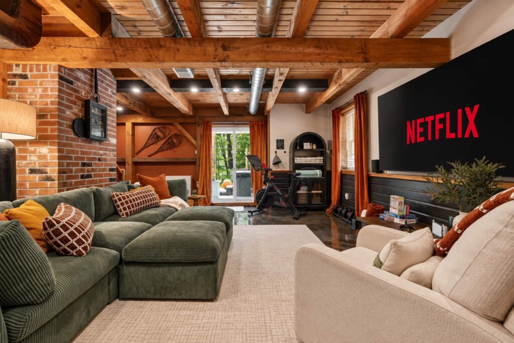 Family room with green sectional sofa, brick wall and large Netflix TV