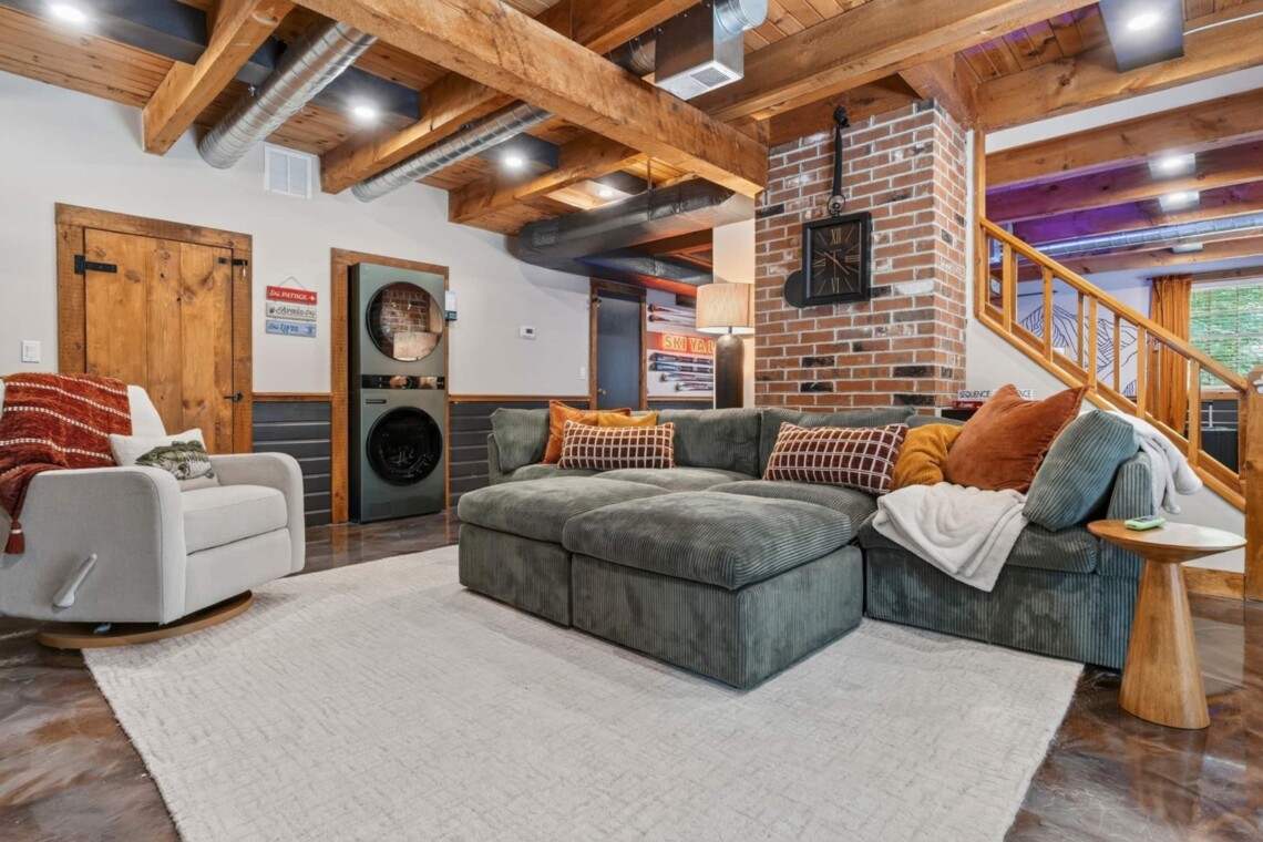 Green sectional sofa in the family room with stacked washer and dryer nearby
