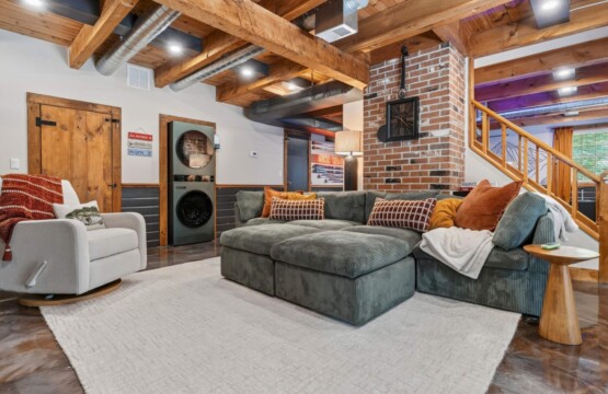 Green sectional sofa in the family room with stacked washer and dryer nearby