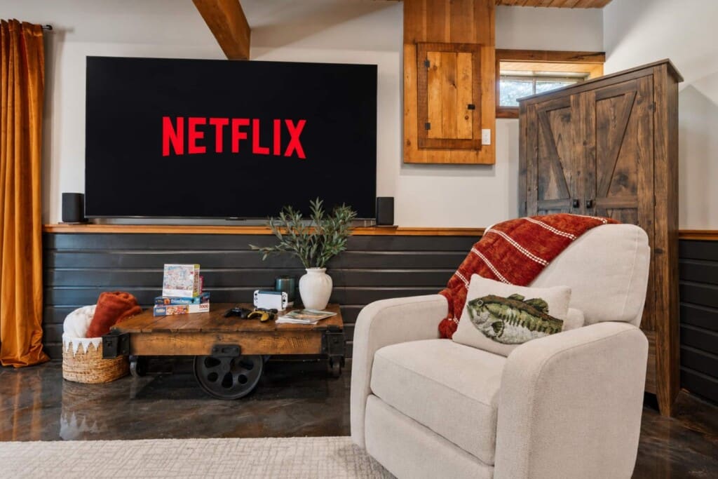 Large wall-mounted TV with armchair and rustic cart coffee table