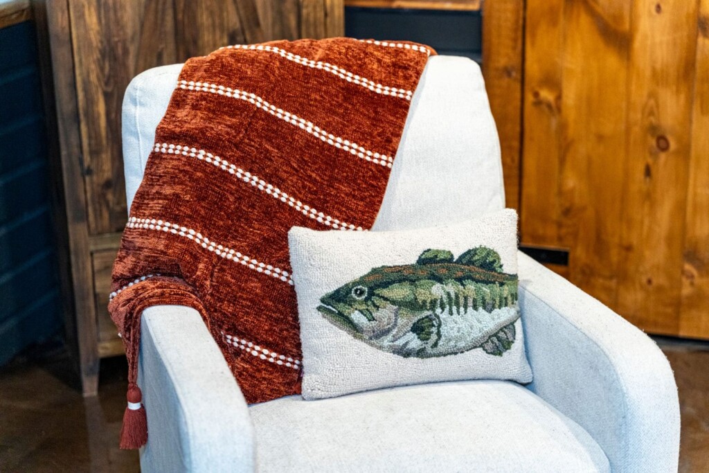 Cream armchair with rust throw blanket and bass fish pillow
