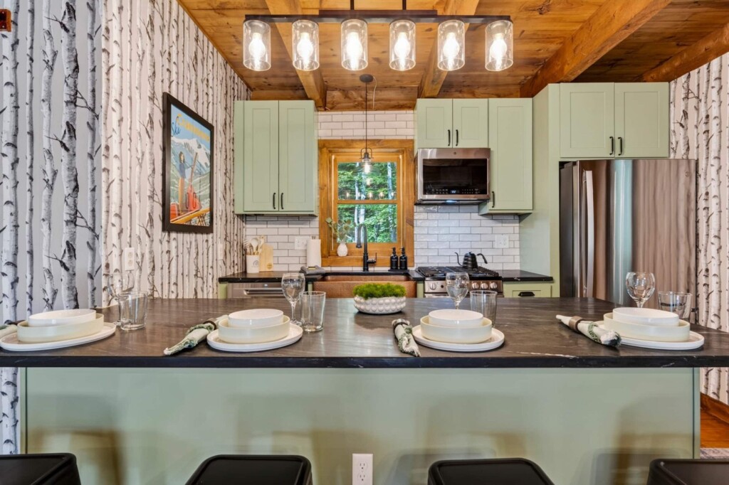 Renovated kitchen with sage green cabinets and island seating at Peak & Pine Retreat