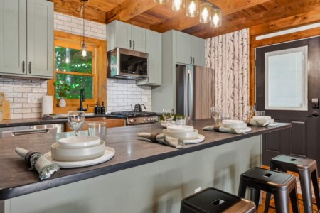Kitchen island with bar stools, place settings and stainless steel appliances