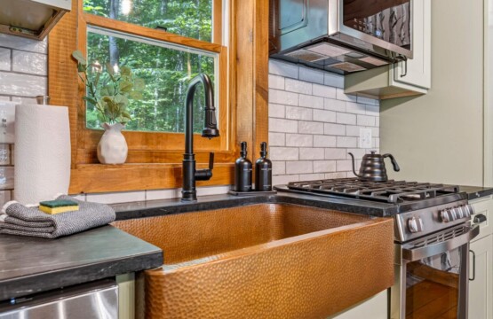 Hammered copper farmhouse sink beside a stainless gas range in the renovated kitchen