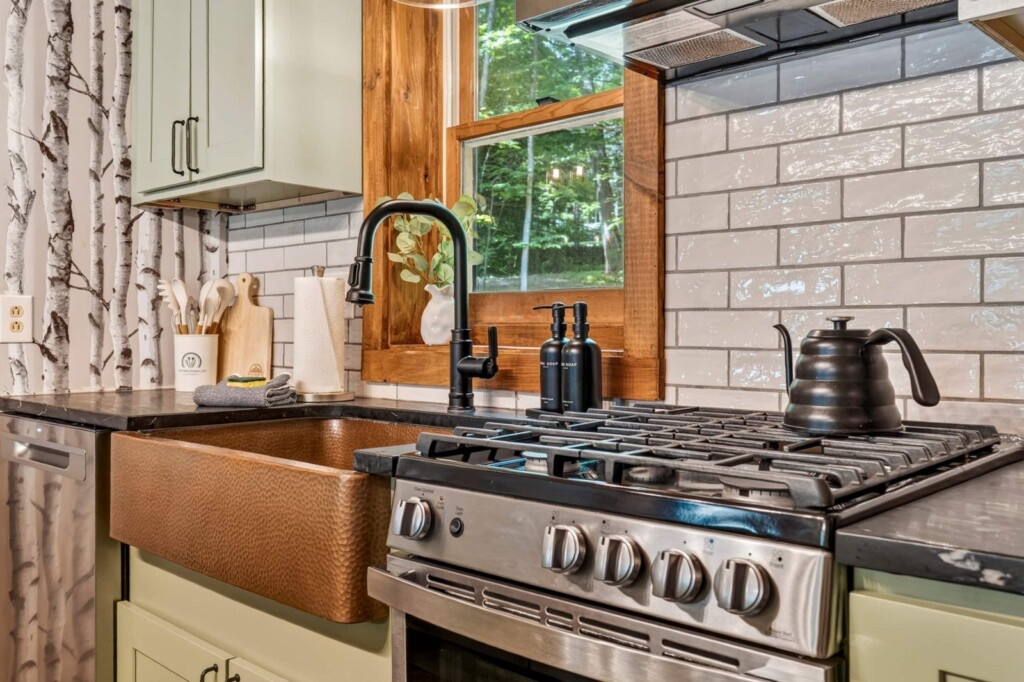 Copper sink, gas range and kettle in the renovated kitchen at Peak & Pine Retreat