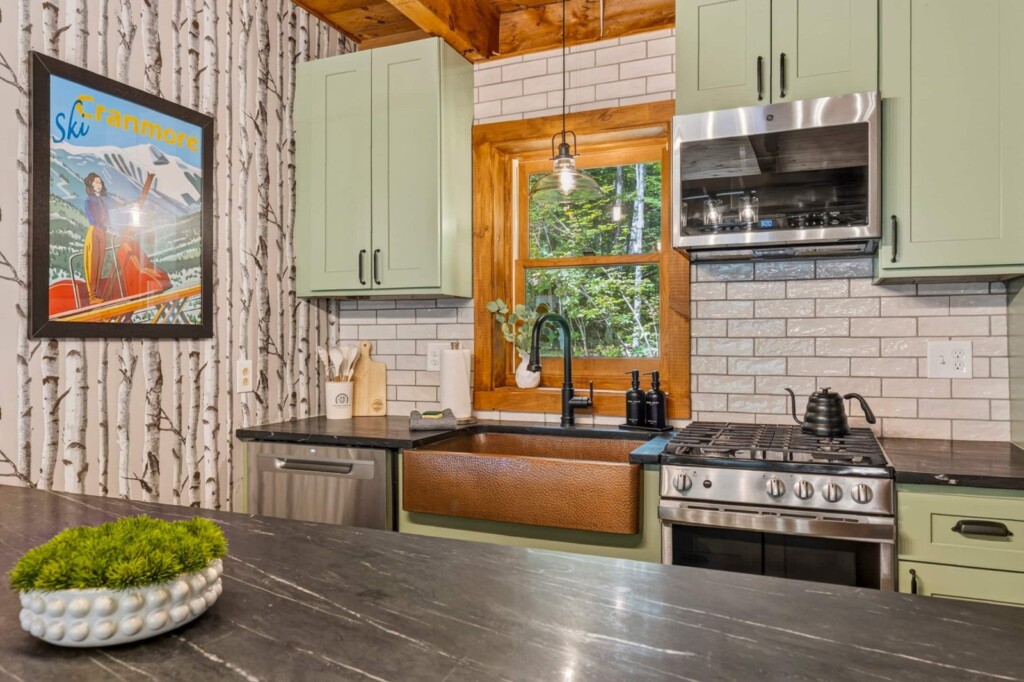 Renovated kitchen with copper sink, gas range and window at Peak & Pine Retreat