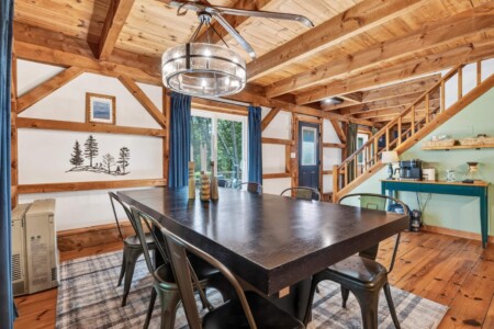 Large dining table under a ceiling fan chandelier at Peak & Pine Retreat