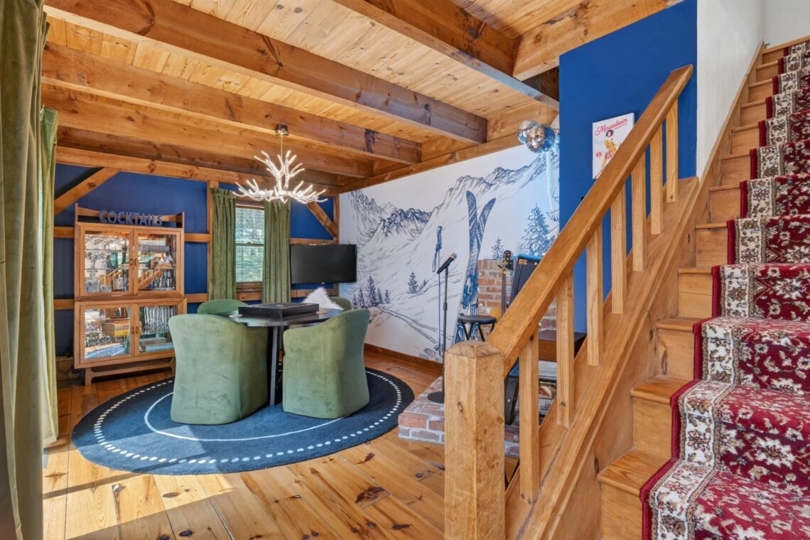 Game nook with green chairs beside a carpeted wooden staircase and ski mural