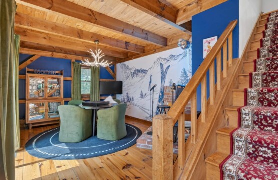 Game nook with green chairs beside a carpeted wooden staircase and ski mural