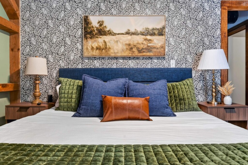 Navy headboard bed with velvet pillows and patterned wallpaper accent wall