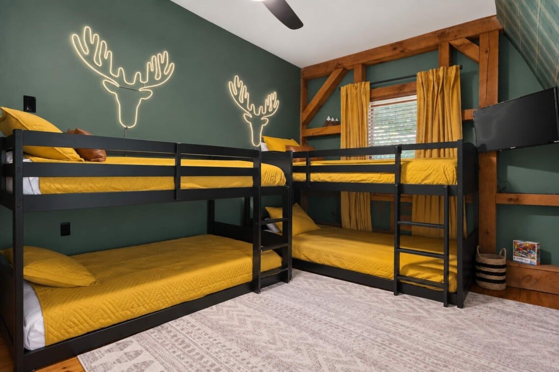 Two bunk beds with mustard bedding and neon antler art at Peak & Pine Retreat