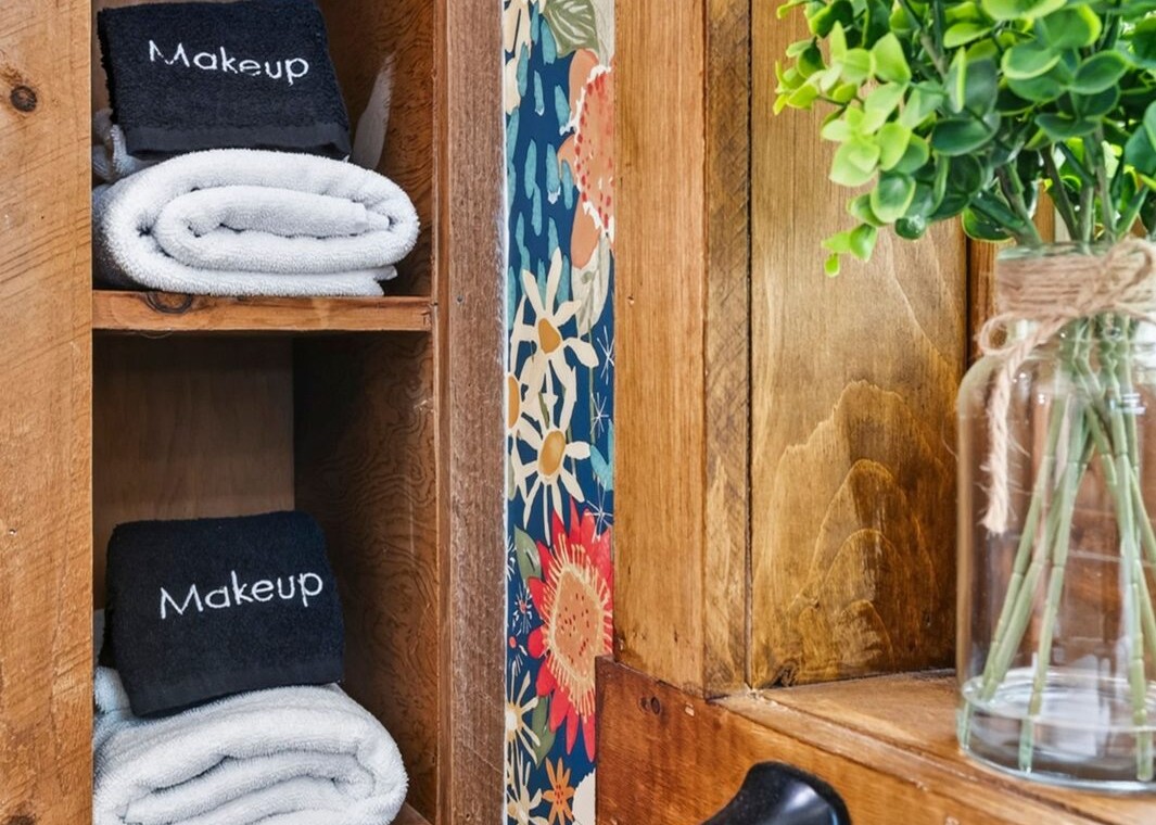 Open shelves with rolled towels and makeup remover cloths in the bathroom