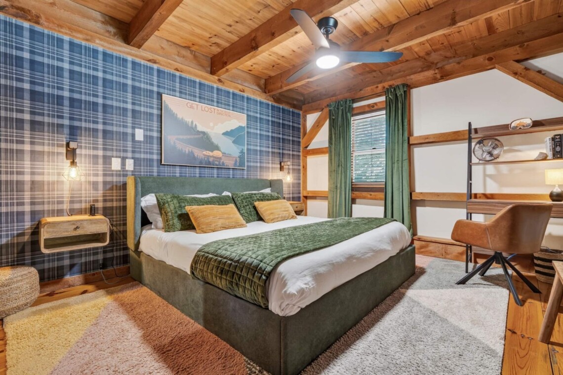 Plaid accent wall bedroom with green quilt, ceiling fan and work desk