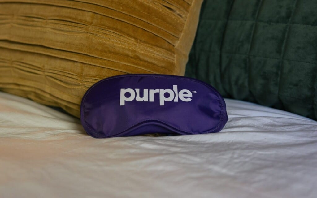 Purple sleep mask on the bed with velvet pillows