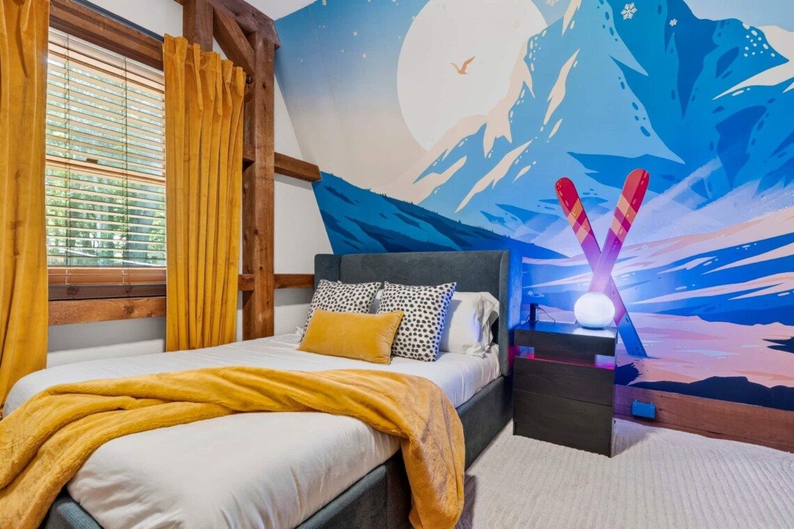 Bedroom with colorful mountain ski mural, crossed ski lamp and mustard throw