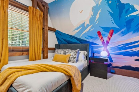 Bedroom with colorful mountain ski mural, crossed ski lamp and mustard throw