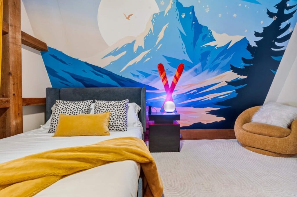 Mountain mural bedroom with crossed ski lamp and cozy round accent chair