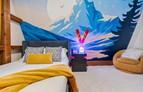 Mountain mural bedroom with crossed ski lamp and cozy round accent chair